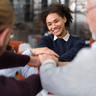 Parceria e colaboração entre equipes no ambiente corporativo Pessoas unindo as mãos em gesto de parceria e trabalho em equipe em reunião corporativa.